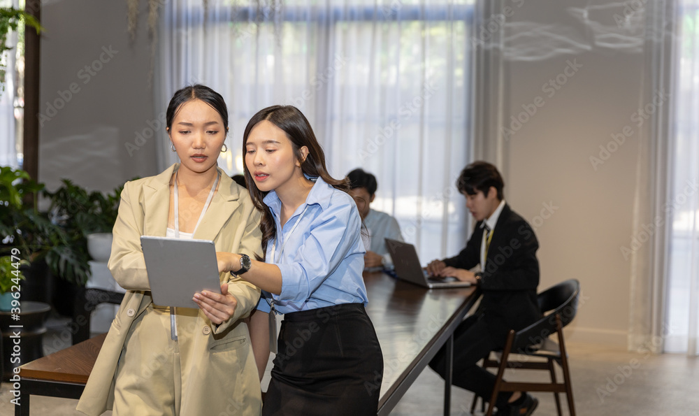 Two business female workers in formal uniform using handheld technology or digital device to check for daily plan. Lifestyle technology is in hands of young entrepreneur ladies Two business female workers in formal uniform using handheld technology or digital device to check for daily plan. Lifestyle technology is in hands of young entrepreneur ladies