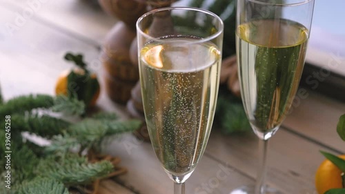 Christmas table at the winter window. Two glasses of champagne, candles in wooden candlesticks and tangerines surrounded by fresh spruce branches.