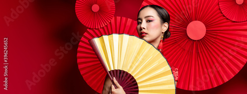 Fotografie Beautiful Asian woman with colorful fashionable make up  holding golden fan in o