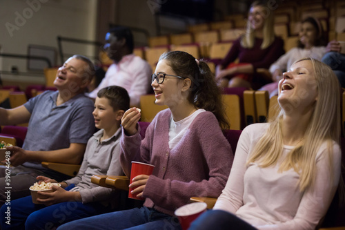 Cheerful parents with tween children watching comedy in cinema. Family leisure and entertainment concept