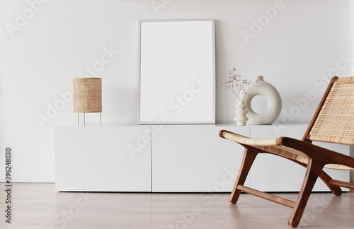 Blank picture frame mockup on white wall. White living room design. View of modern scandinavian style interior with chair. Home staging and minimalism concept