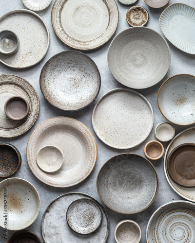Fototapeta handmade ceramics, empty craft ceramic plates and bowls on light background, top
