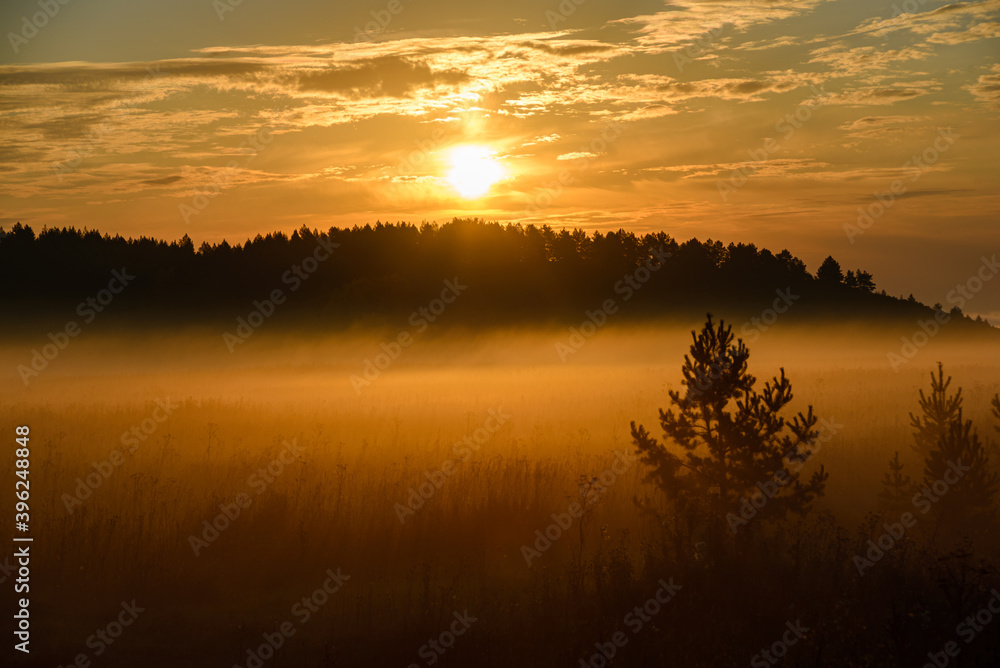 Sunrise, in the foreground a field covered with a thin layer of fog Sunrise, in the foreground a field covered with a thin layer of fog