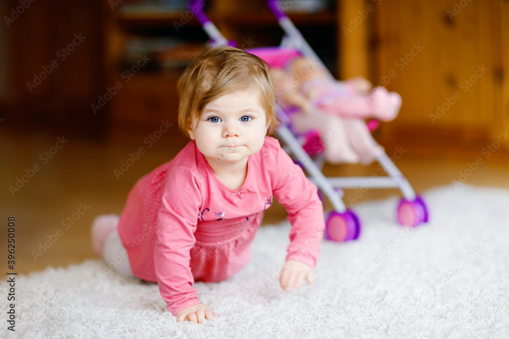 Cute adorable baby girl crawl and play with doll carriage. Beautiful toddler child with pushing stroller with toy at home. Happy kid with two dolls Cute adorable baby girl crawl and play with doll carriage. Beautiful toddler child with pushing stroller with toy at home. Happy kid with two dolls