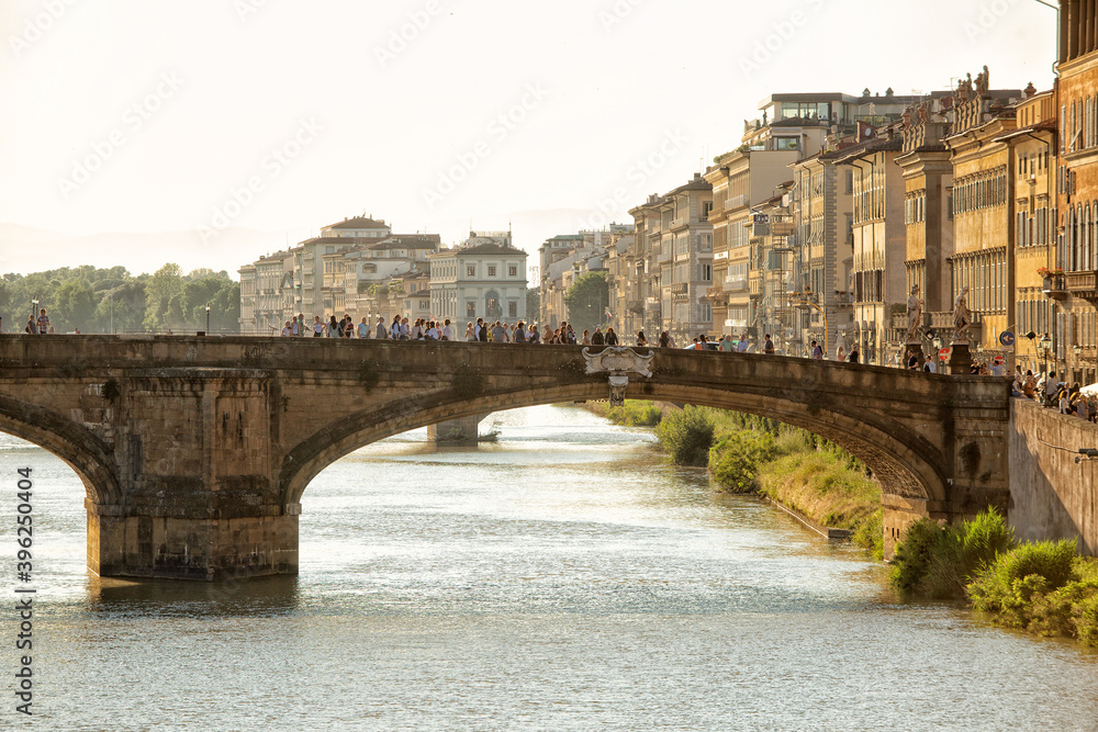 Obraz premium Tourists gather on the Holy Trinity Bridge(Ponte Sanata Trinita) that crosses the Arno river in the late afternoon