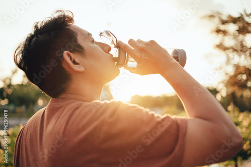 handsome man drinking water on a sunny day after running. Sport, fitness workout concept.