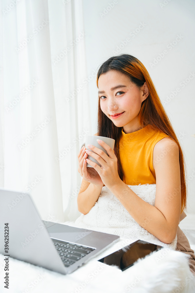 Beautiful asian woman holding cup of coffee at laptop computer desk. Beautiful asian woman holding cup of coffee at laptop computer desk.