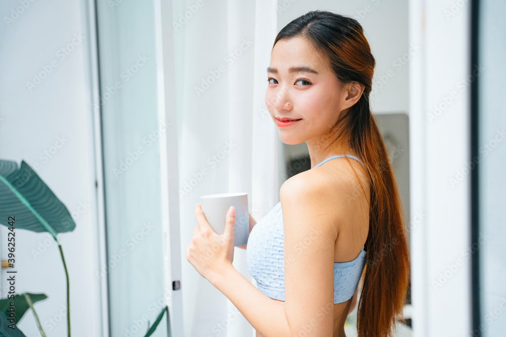 Beautiful sporty woman wearing sportbra holding cup of coffee at home balcony. Beautiful sporty woman wearing sportbra holding cup of coffee at home balcony.