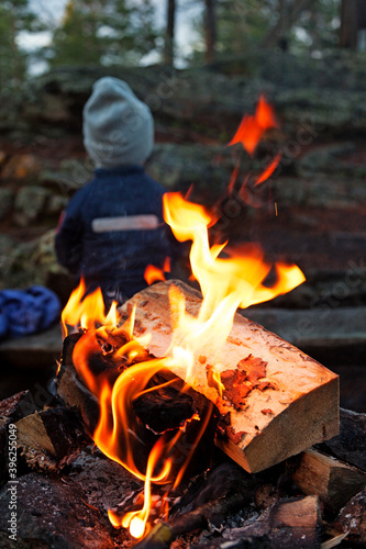 Umea, Norrland Sweden - October 20, 2020: little boy warms his back by a campfire