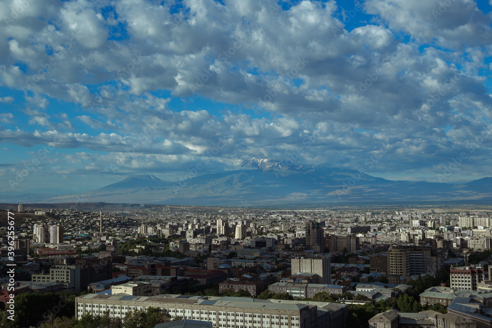 Scenery of city of Yerevan with rooftops of residential buildings on sunny day on background of mountain range in Armenia 