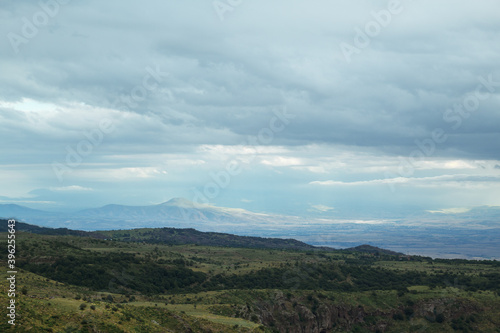 Mountainous valley in highlands covered with green forests on cloudy day 