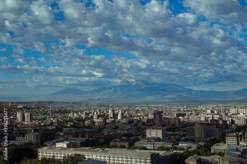 Scenery of city of Yerevan with rooftops of residential buildings on sunny day on background of mountain range in Armenia 