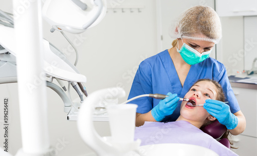 Female dentist with girl patient during oral checkup in modern dentistry.