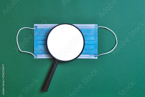 Protective mask and magnifier on a green background. Mock up.