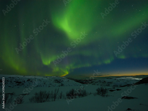 Night sky . Northern Lights . Hills in winter. Large stones.