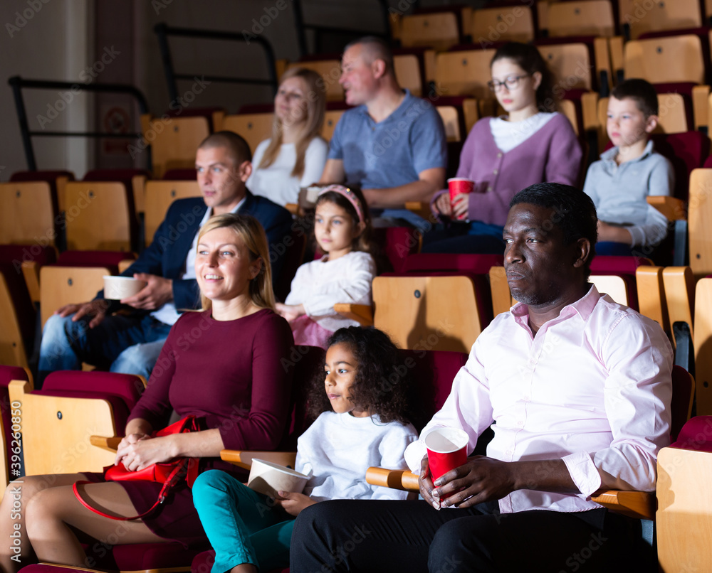 Obraz premium international parents with children sitting at movie in cinema