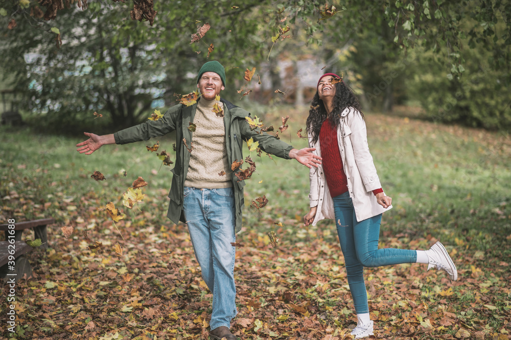 Fototapeta premium Young couple enjoying playing with beautiful autumn leaves