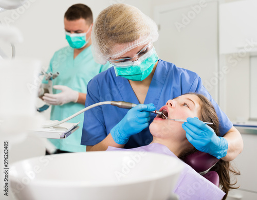 Female dentist with girl patient during oral checkup in modern professional dentistry