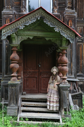 Girl in kokoshnik. Pogorelovo terem. Ancient wooden house with carved windows, ornamental frames in Pogorelovo village, Chukhloma, Kostroma region, Russia. Traditional russian style, old architecture photo
