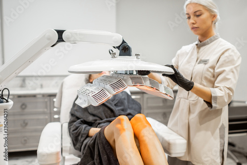 Woman doing led light therapy on her legs with a doctor at luxury medical office. Concept of a Healite treatment photo