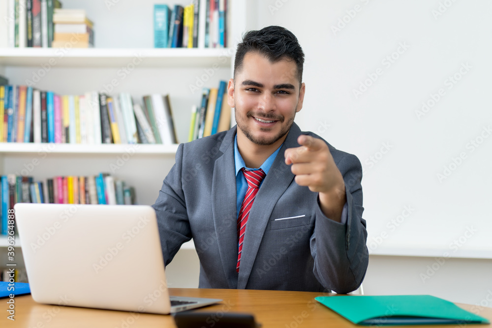 Laughing mexican businessman at computer at office Laughing mexican businessman at computer at office