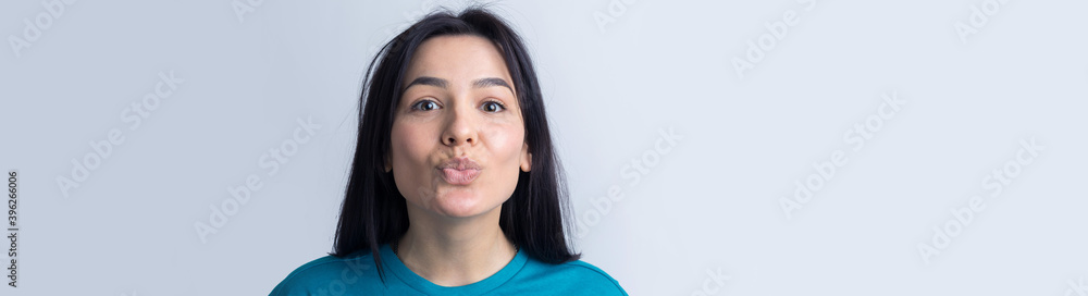 Portrait of flirting young woman blowing air kiss isolated over grey background Portrait of flirting young woman blowing air kiss isolated over grey background