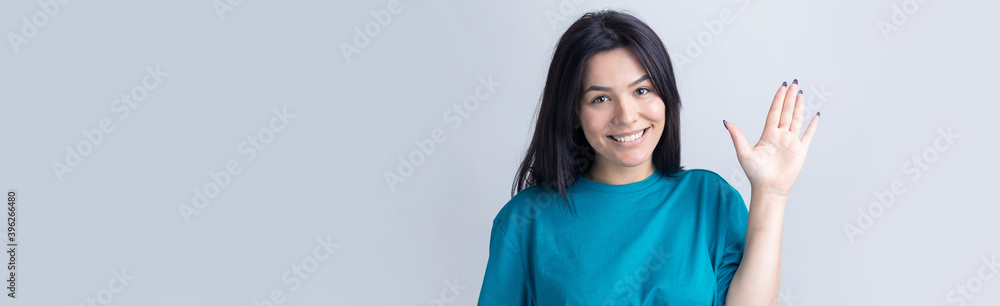 Smiling woman raised her hand palm up and forward like waving. Smiling woman raised her hand palm up and forward like waving.