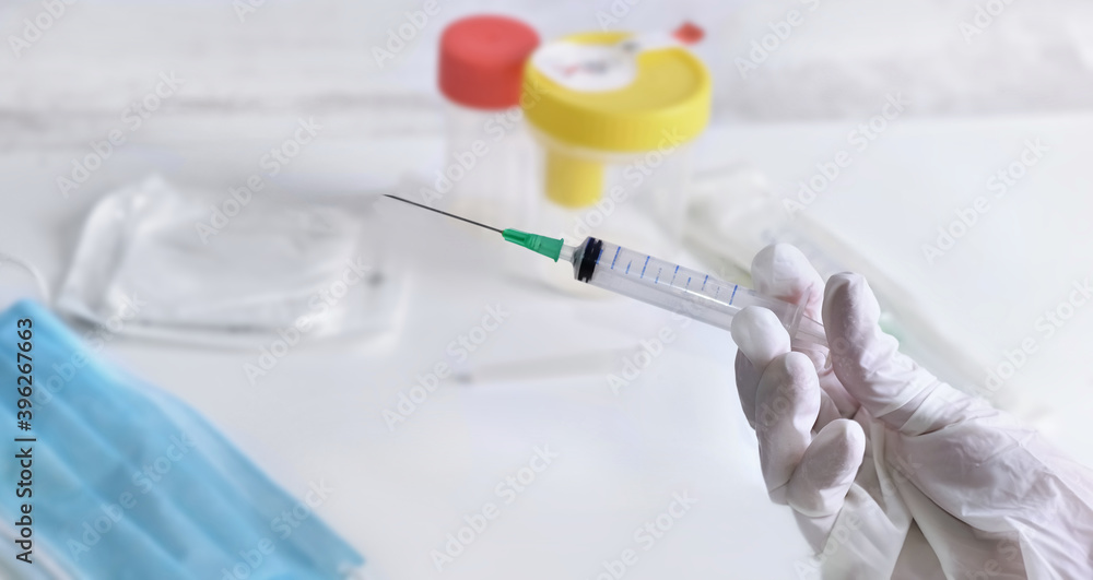 close on a hand with a glove holding a syringe above a table with pharmacy close on a hand with a glove holding a syringe above a table with pharmacy