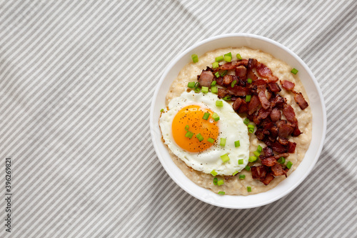 Homemade Cheesy Bacon Savory Oatmeal Bowl on cloth, view from above. Top view, overhead, flat lay. Copy space.