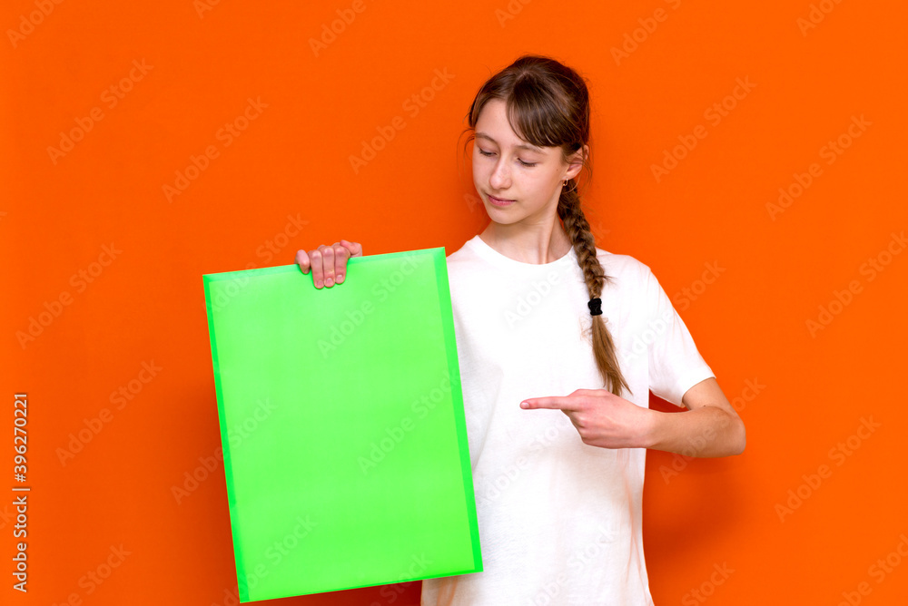 Surprised caucasian young long haired girl holding and poke at bright green folder with a banner advertisement Surprised caucasian young long haired girl holding and poke at bright green folder with a banner advertisement
