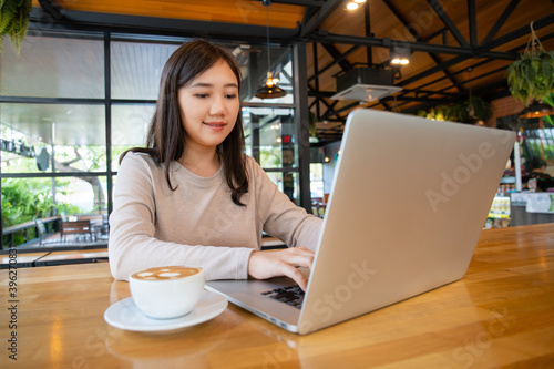 Asian beautiful working woman doing her work and drink in the coffee shop or cafe. Free Download Asian beautiful working woman doing her work and drink in the coffee shop or cafe. - GFXLoad
