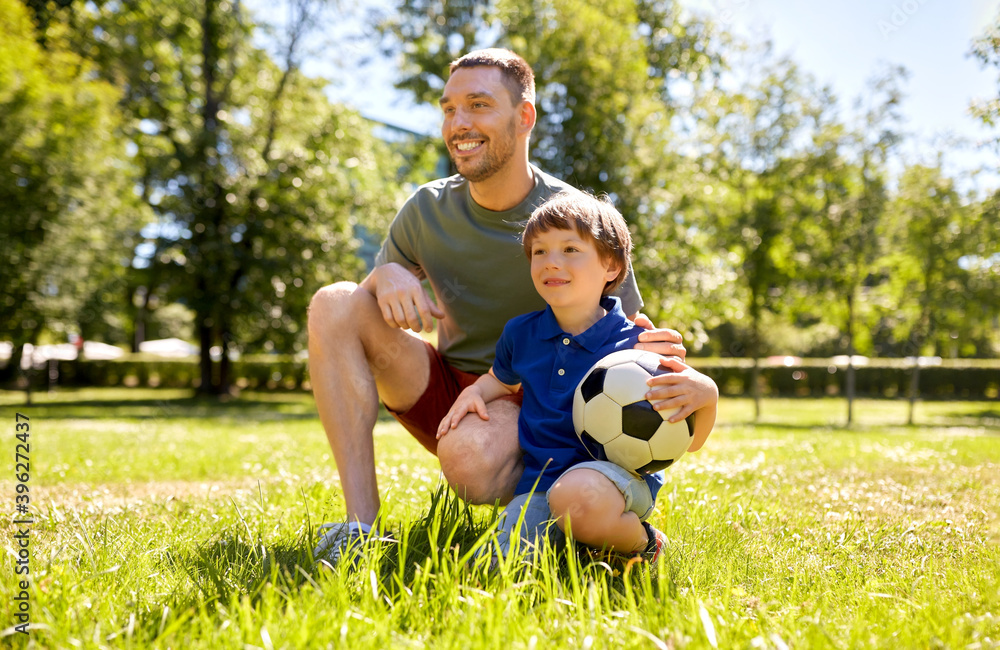 Obraz premium family, fatherhood and people concept - happy father and little son with soccer ball at summer park
