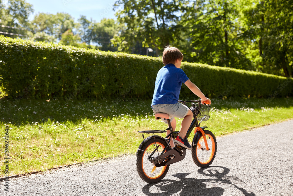 childhood, leisure and people - little boy riding bicycle at summer park