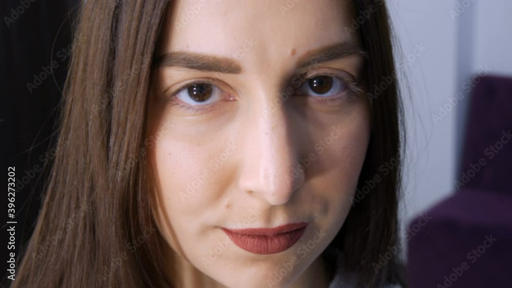 The face of a young girl before a modern eyelash lamination procedure in a professional beauty salon before the eyelash curling procedure. Portrait of a woman without makeup with dark lipstick. The face of a young girl before a modern eyelash lamination procedure in a professional beauty salon before the eyelash curling procedure. Portrait of a woman without makeup with dark lipstick.