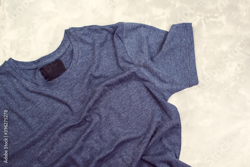 T-shirt mockup, flat lay. Dark blue t-shirt on concrete grey background,