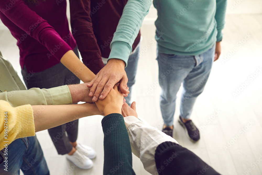 High angle close-up of team of people joining their hands united by a common goal High angle close-up of team of people joining their hands united by a common goal