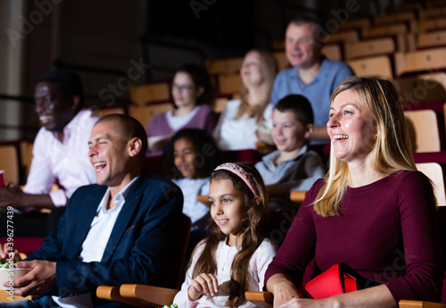 parents with children laughting at movie in cinema