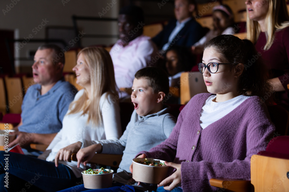 Obraz premium Portrait of emotional teen girl looking scared or shocked while watching movie in cinema