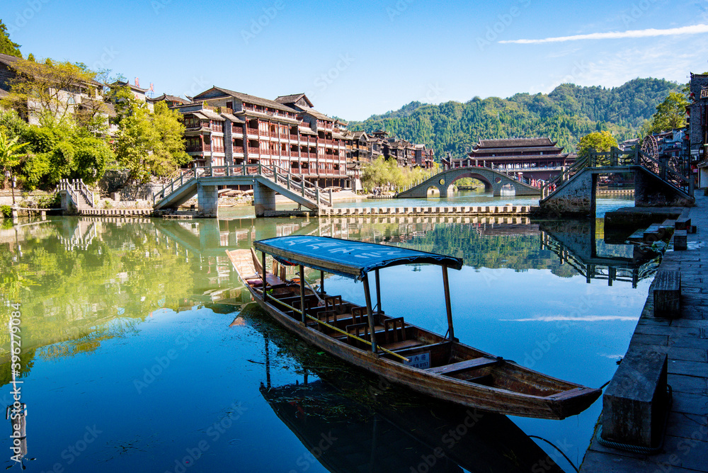 the river, the boat, stone bridge and the old houses at ancient phoenix town in the morning at Hunan, China.