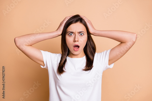 Photo portrait of amazed shocked frustrated stressed girl keeping head with hands isolated pastel beige color background