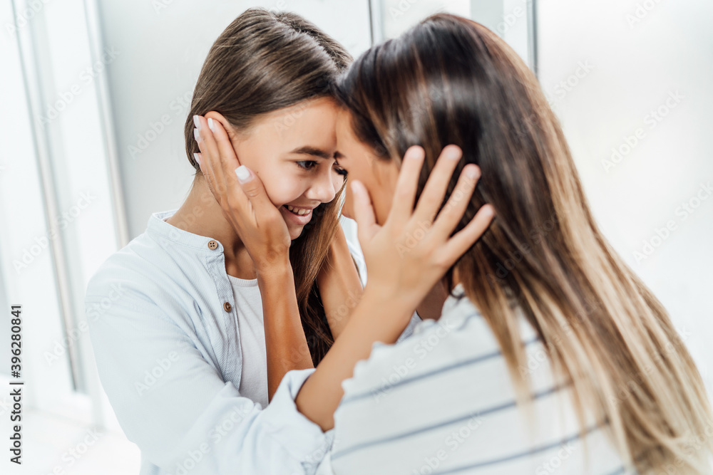 Mom and daughter hugging touching face. Connection between them Mom and daughter hugging touching face. Connection between them