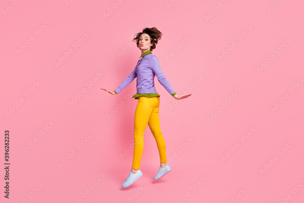 Full length profile photo of funny lady jump up sending air kisses wear jumper pants shoes isolated pink color background