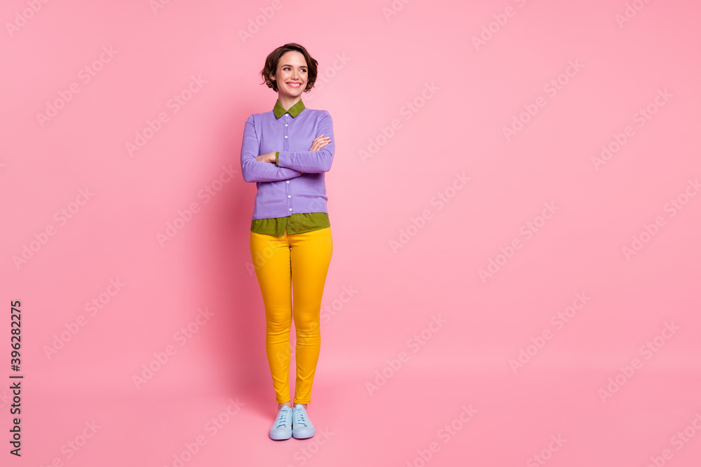 Full length photo of attractive lady arms crossed look side empty space wear jumper pants sneakers isolated pink color background Full length photo of attractive lady arms crossed look side empty space wear jumper pants sneakers isolated pink color background