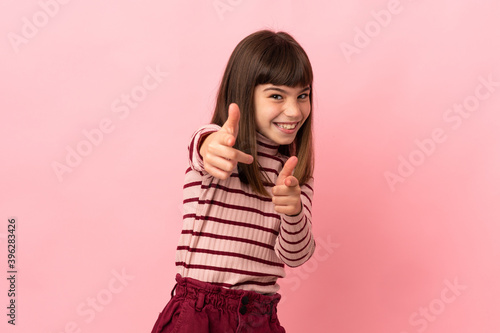 Little girl isolated on pink background surprised and pointing front © luismolinero