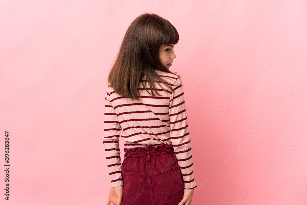 Little girl isolated on pink background in back position and looking side Little girl isolated on pink background in back position and looking side