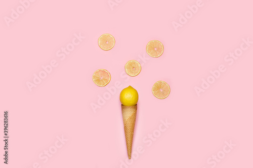 Cono de oblea con un limón y rodajas sobre un fondo rosa liso y aislado. Vista superior. Copy space