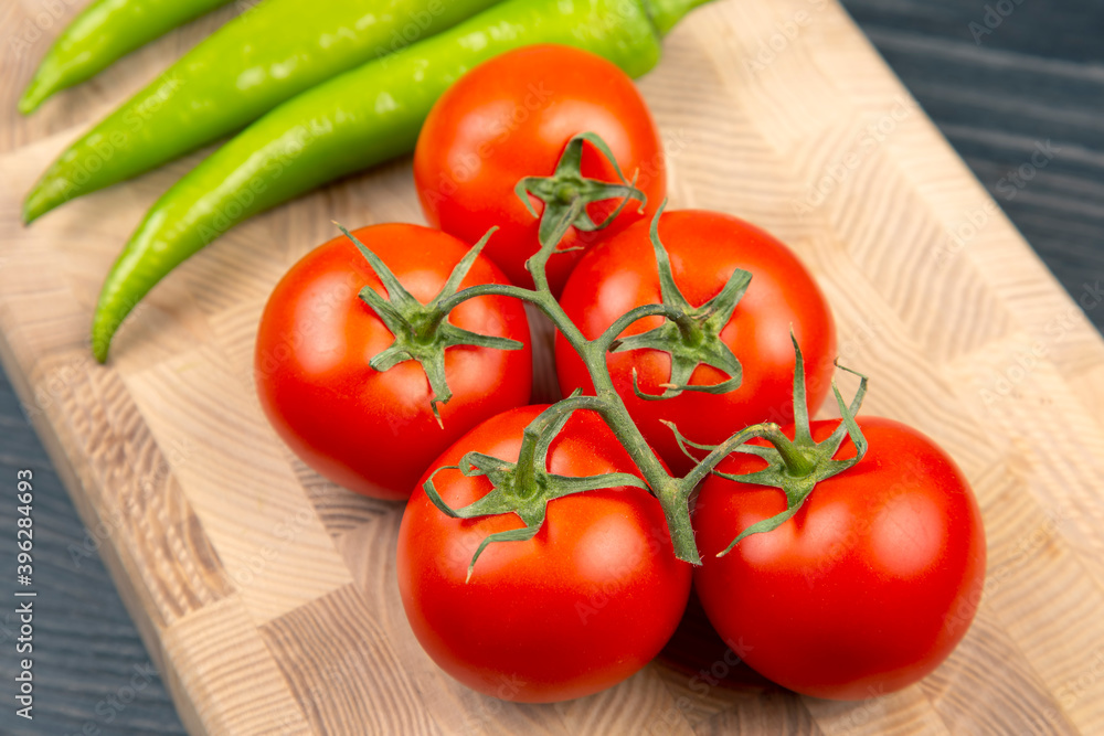red tomatoes and green hot peppers on a kitchen board red tomatoes and green hot peppers on a kitchen board