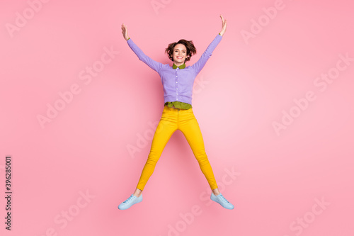 Full length photo of careless childish girl jump raise hands isolated over pastel color background
