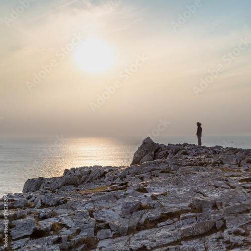 Silhouette d'une personne admirant le paysage de la pointe de Pen Hir en Bretagne au coucher de soleil photo