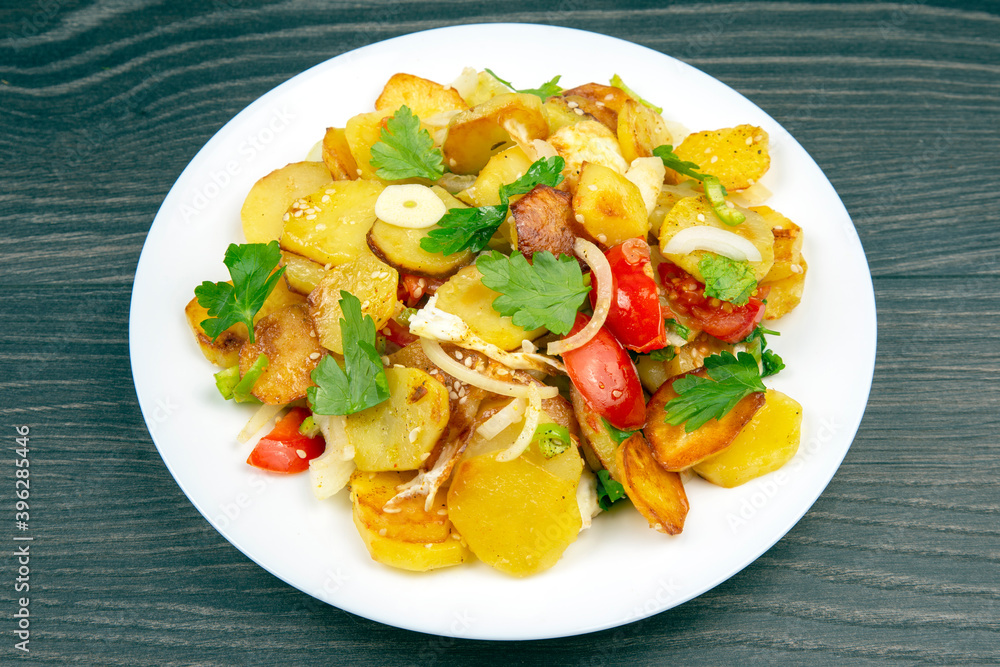 cooked fried potatoes with herbs and vegetables in a white plate on a wooden table cooked fried potatoes with herbs and vegetables in a white plate on a wooden table